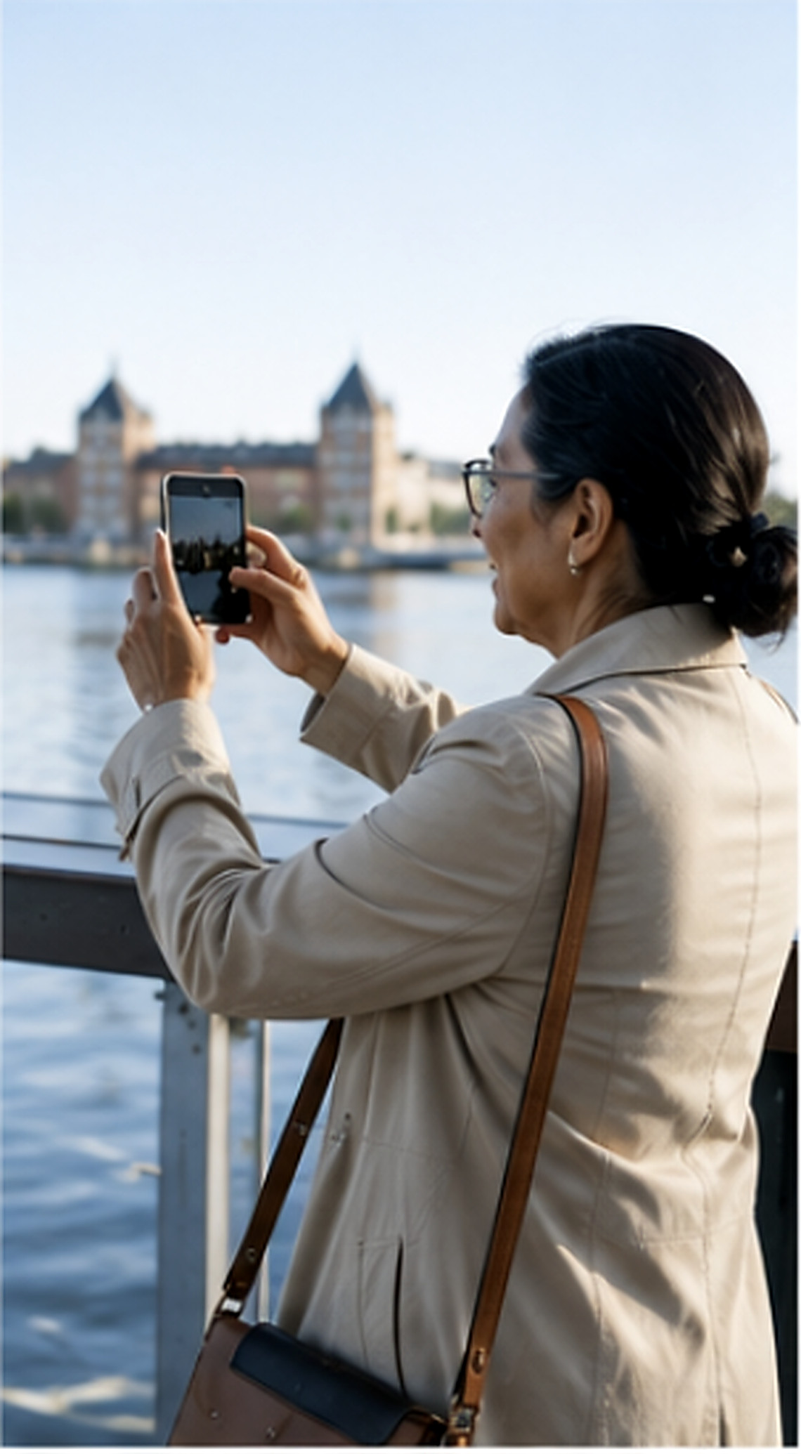 A woman taking a photo with her phone by the water
